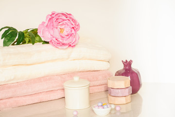 Bath setting in white and pink colors. Towel, aroma oil, flowers, soap. Selective focus, horizontal.