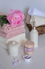 Fototapeta na wymiar Bath setting in white and pink colors. Towel, aroma oil, flowers, soap. Selective focus, horizontal.