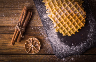 Fototapeta na wymiar Waffle sprinkled with powdered sugar on a wooden background.