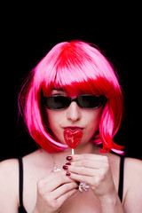 Beauty Woman With Pink Wig And Sunglasses and holding with her hand a candy with heart shape