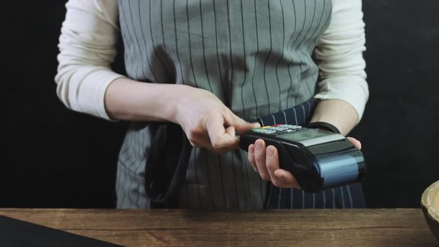 Cropped view of woman swiping credit card through credit card reader