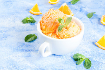 Homemade organic orange sorbet with orange slices and mint leaves. On a blue stone table   copy space