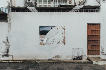 White Clean Wall with Rusted Red Wall with Ripped Poster Trace from The Street of George Town. Penang, Malaysia.
