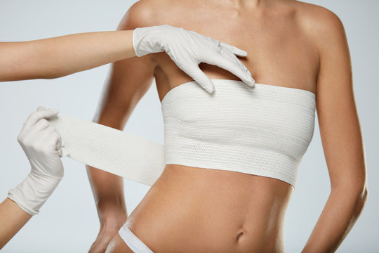 Plastic Surgery. Doctor Hands Wrapping Female Breast In Bandage
