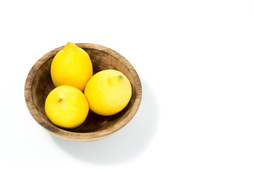 Lemons in a natural handmade real wood bowl isolated in white background - view from the top