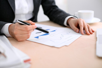 Fototapeta premium Business woman sitting at the table and examines the financial results
