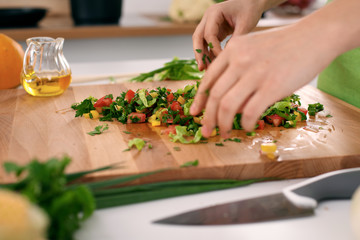 Close up of  woman's hands cooking in the kitchen. Housewife slicing ​​fresh salad. Vegetarian and healthily cooking concept
