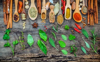Washable wall murals Herbs Various of spices and herbs in wooden spoons. Flat lay of spices ingredients chilli ,pepper corn, garlic, thyme, oregano, cinnamon, star anise, nutmeg, mace, ginger and bay leaves on shabby wooden.