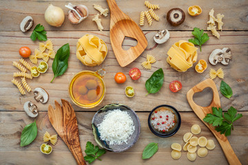 Fototapeta na wymiar Italian foods concept and menu design.Various kind of pasta with ingredients sweet basil ,tomato ,garlic ,parsley ,champignon and extra virgin olive oil on wooden background flat lay.