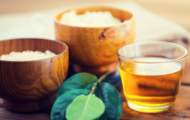 close up of honey in glass with leaves on wood