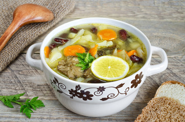 Vegetable soup with mushrooms and lemon on old wooden table