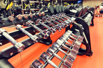 close up of dumbbells and sports equipment in gym