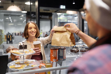 woman taking paper bag from seller at cafe
