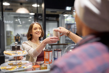 happy woman taking coffee cup from seller at cafe