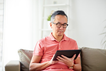 man with tablet pc sitting on sofa at home