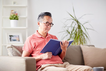 man sitting on sofa and reading book at home