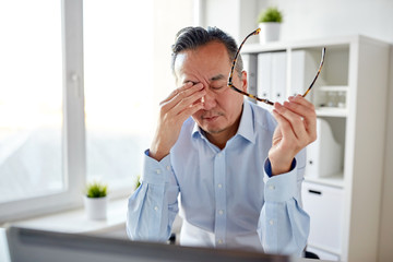 tired businessman with glasses at laptop in office