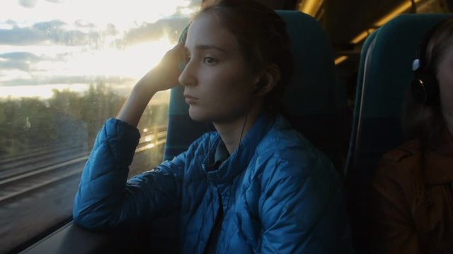 Young brunette hipster girl looking to the window in the train and thinking about her future.