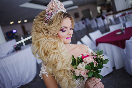 Young fashion bride with perfect skin and make up, curly hair, flowers and tiara on the head, indoors
