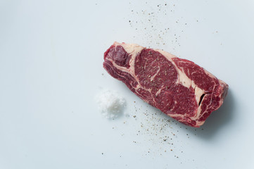 top view of uncooked Spencer Roll beef steak with salt and pepper on white background with copy space