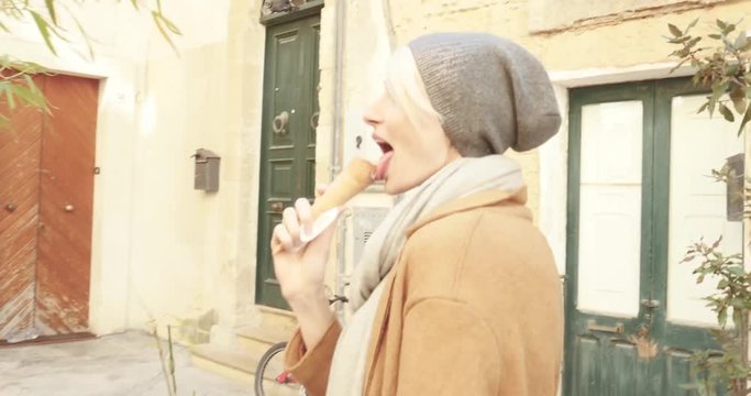 Beautiful young caucasian woman eating ice cream, smiling, relaxing. Italy.