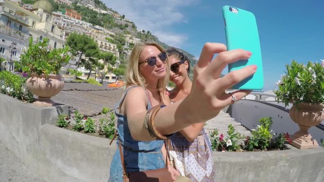 Tourist Girl Friends taking selfies smiling on summer fun travel adventure in Amalfi for social media with smart phone 