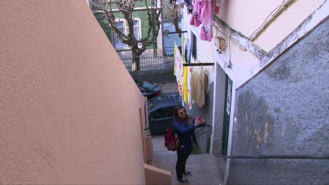Tourist girl with a back pack taking selfie photo on smartphone between two building walls in old Portugal town Sintra