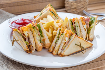 Club Sandwich with Cheese, Pickled Cucumber, Tomato and Smoked Meat. Garnished with French Fries
