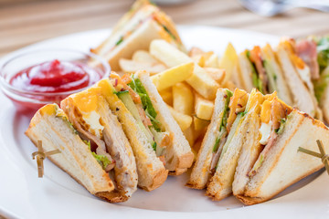 Club Sandwich with Cheese, Pickled Cucumber, Tomato and Smoked Meat. Garnished with French Fries