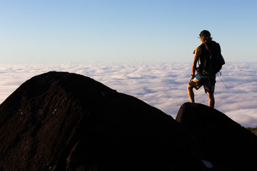 A mountaineer looks over a view above the cloud tops from the summit of a mountain in Australia.