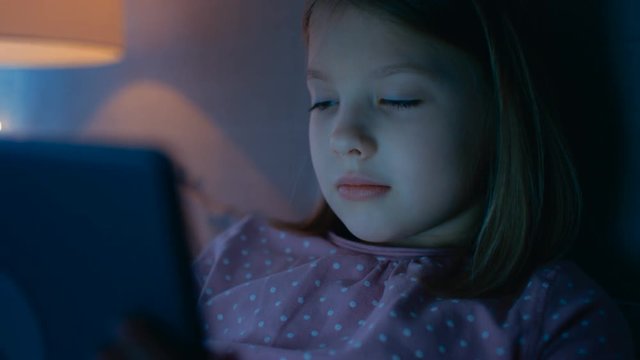 Close-up of a Cute Young Girls Face while She's Looking at Tablet Computer that Illuminates Her Face. Shot on RED EPIC-W 8K Helium Cinema Camera.