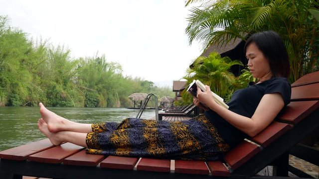 Asian woman reading a book on the houseboat