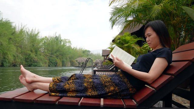 Asian woman reading a book on the houseboat