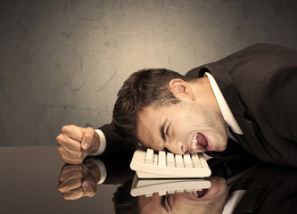 Obraz premium Frustrated businessman's head on keyboard