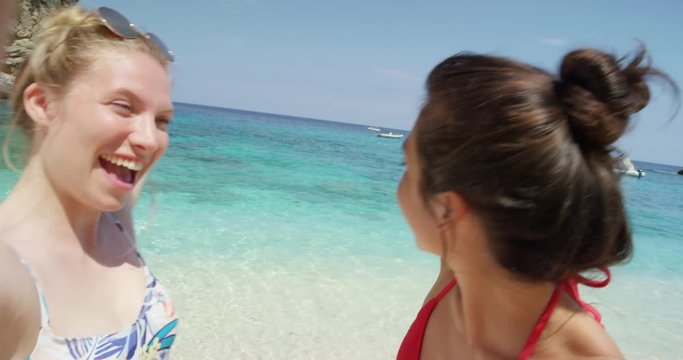 Best friends having video chat using smart phone on beach taking selfie photograph smiling blowing kiss waving enjoying tropical nature background view on  summer vacation travel adventure POV