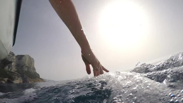 Womans hands touching ocean waves on boat inspiration flowing freedom on adventure travel vacation 