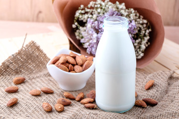 Almond milk in glass bottle on wood background