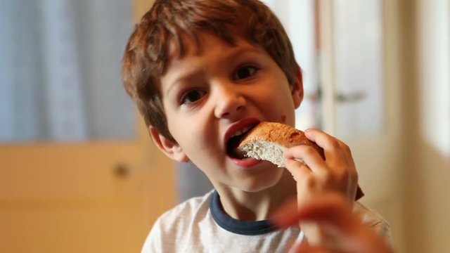 Young boy eating bread with marmalade. Kid eating breakfast in the morning