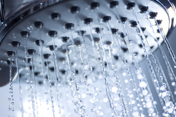 Naklejka na ściany i meble Image of a modern shower head splashing water close up background.