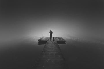 A man standing on wooden jetty thinking about the future. A concept of people and life.