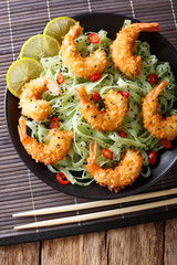 Shrimp in breading with green tea pasta and sesame close-up on a plate. vertical top view