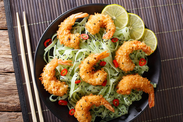 Shrimp in breading with green tea pasta and sesame close-up on a plate. horizontal top view