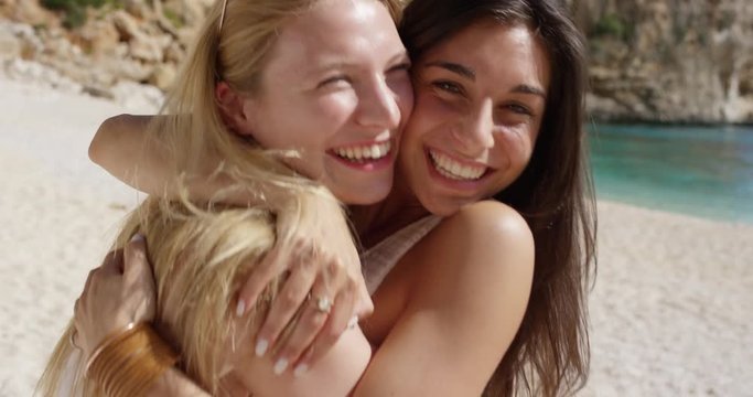 Best friends hugging two cute girl teenagers giving kiss on cheek woman on tropical beach summer vacation 
