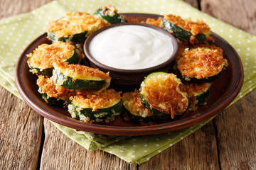 Homemade zucchini slices in breadcrumbs with sour cream close-up. horizontal