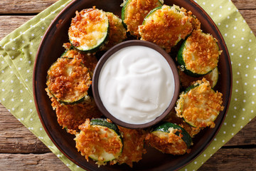 Delicious slices of zucchini in breadcrumbs with sour cream close-up. Horizontal top view