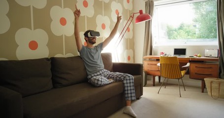 Young Man wearing virtual reality headset at concert performance sitting on sofa at home watching 360 video imagination concept in retro styled modern apartment - Powered by Adobe
