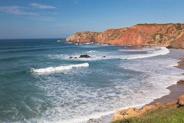 travel to colorful amado beach with waves on atlantic coastline, algarve, portugal 