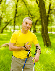 Senior man with pain on heart during nordic walking