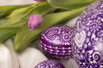 purple eastern egg on white cloth with purple tulip