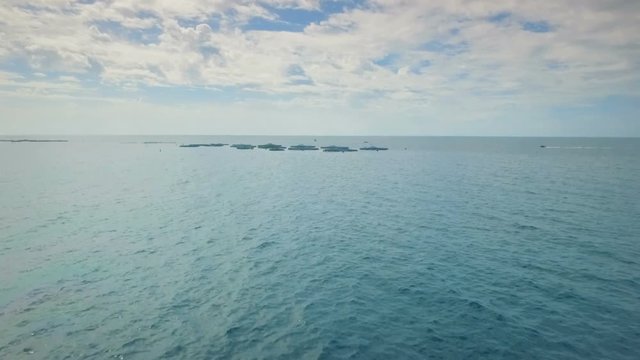 Aerial - Flying above fish farm in the Atlantic Ocean Canary Islands with circular cages for breeding Dorado and Seabass fish
